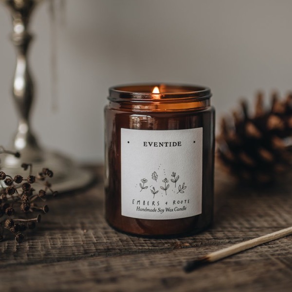 Eventide soy candle, lit, on a weathered wooden surface