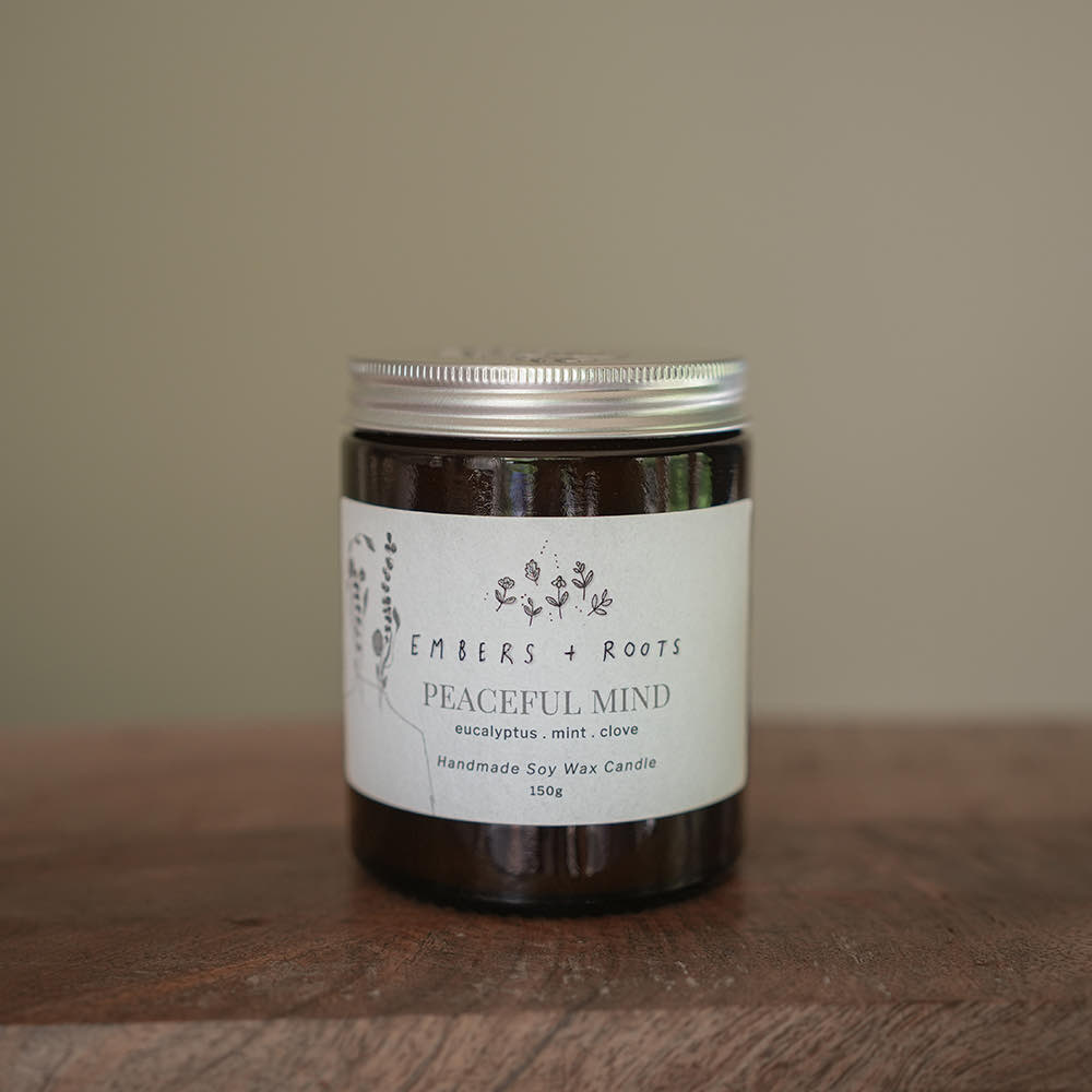 An Embers & Roots medium soy candle on a wooden table